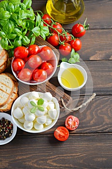 Italian food ingredients Ã¢â¬â mozzarella, tomatoes, basil and olive oil on rustic wooden table.